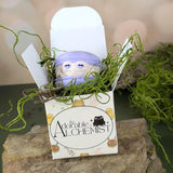 A single macaron frog nestled in moss inside an open Adorable Alchemist blind box.