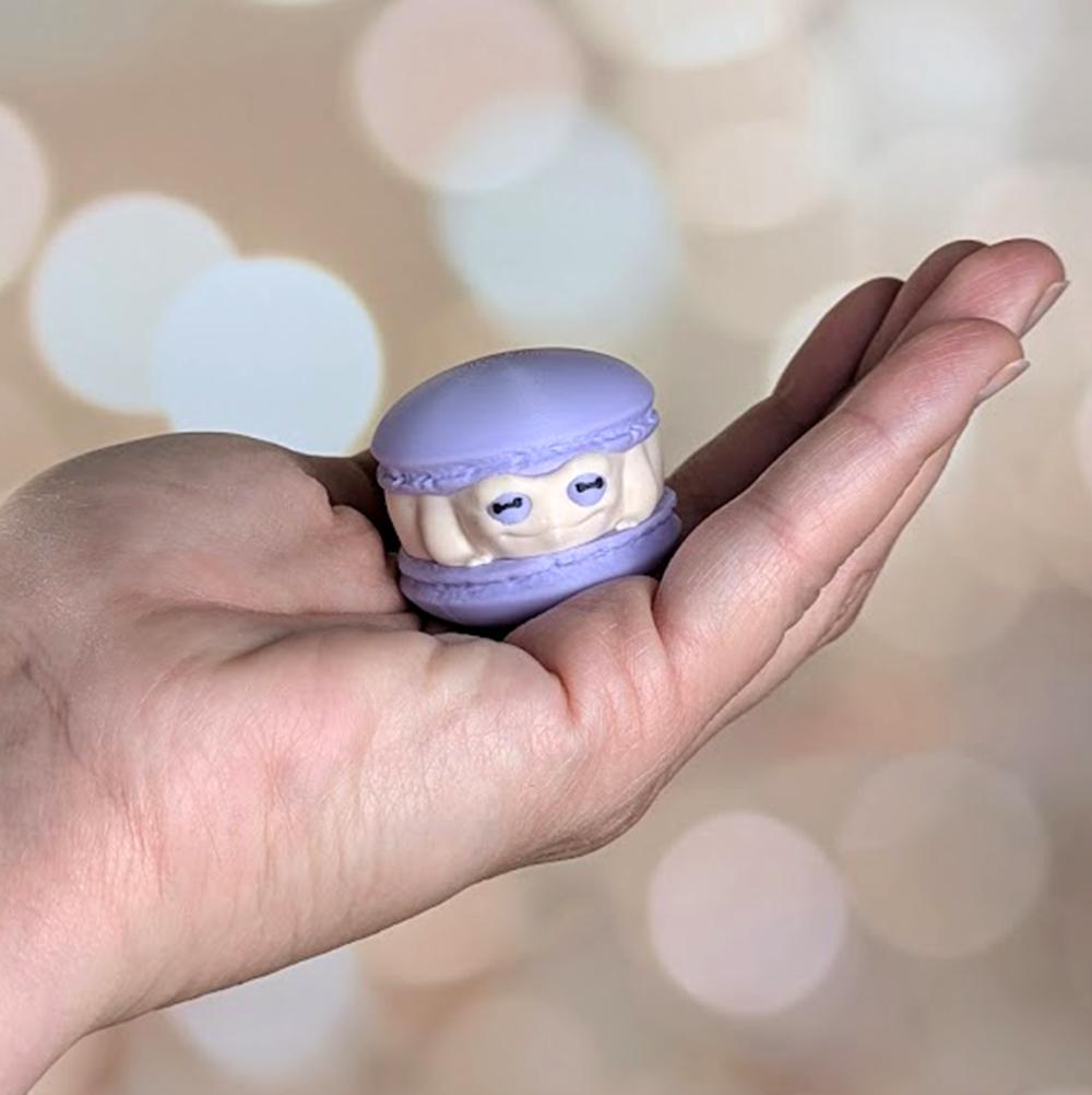 A pastel macaron frog resting in the palm of a hand, showing scale and front detail.