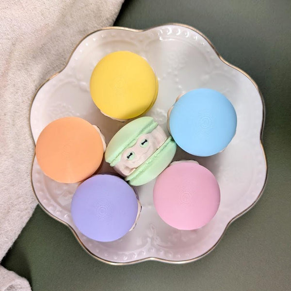 A top down view of pastel-colored macaron-shaped frogs on a decorative plate.
