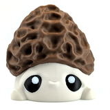 An adorable morel mushroom figurine with big eyes and a sweet face sits on a white background.