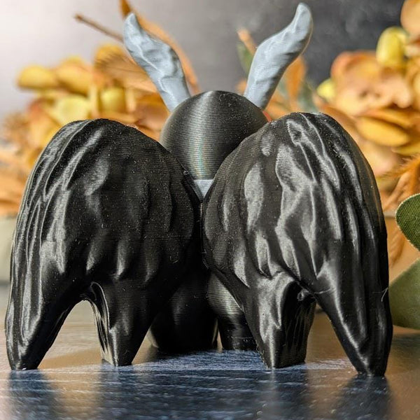 Back view of Mothman showing detailed wings and curled antennae, framed by golden fall foliage.