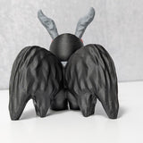 Back view of Mothman figurine with black textured wings and curled gray antennae.