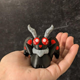 Mothman figurine with red eyes held in hand for scale, against a dark textured background.