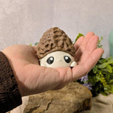 Mushroom goblin figurine with morel cap cradled in a hand for size reference,