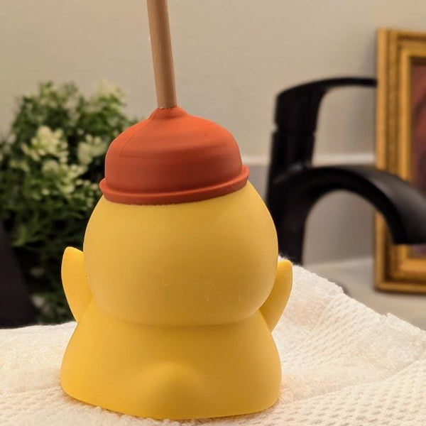 Back view of plunger hat duck figurine, posed in a bathroom scene with faucet in the background.
