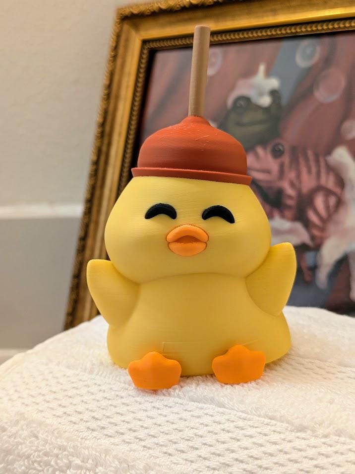 Full front view of cheerful yellow duck figurine wearing a red plunger hat, posed with wings outstretched.