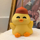Full front view of cheerful yellow duck figurine wearing a red plunger hat, posed with wings outstretched.