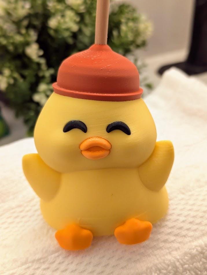 Full front view of cheerful yellow duck figurine wearing a red plunger hat, posed with wings outstretched.