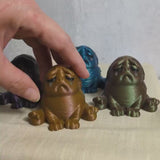 Short video featuring three sad Squonk figurines in different colors, each perched in a hand and embodying the crushing weight of their own self-awareness.