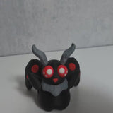 Video clip of the red-eyed Mothman figurine with fuzzy antennae and outstretched wings, radiating mysterious cryptid energy.