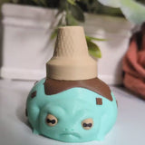 Video thumbnail showing a mint-colored frog with chocolate chips and a tipped ice cream cone hat, embracing its dessert destiny.