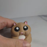 Video thumbnail showing a person holding a chubby hamster figurine in their hand.