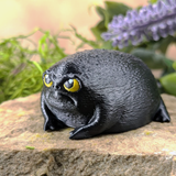 Left side view of the angry black frog figurine, highlighting its rotund shape and subtle leg definition.