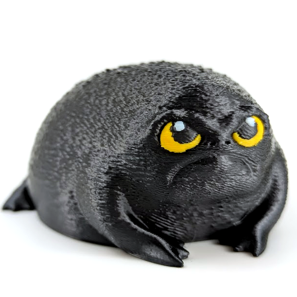 Rage nugget is a black Rainfrog with a sour expression. He has yellow eyes that are full of disdain. He is black in color and looks like an angry avocado.