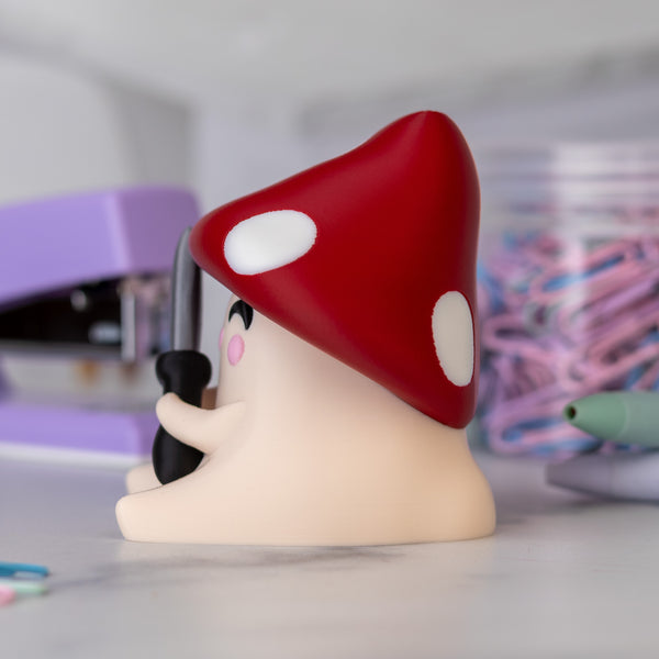 Mushroom-shaped figurine with a red cap and white spots on a blurred background