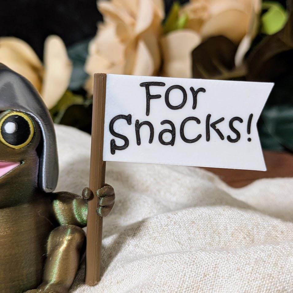 Close-up of Sir Glorb™ with “For Snacks!” battle flag partially in frame and one eye peeking in.