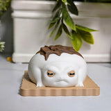 Front-facing close-up of a frog figurine styled like a s’more, with big eyes and a chocolate accent on its back, sitting neatly on a graham base.