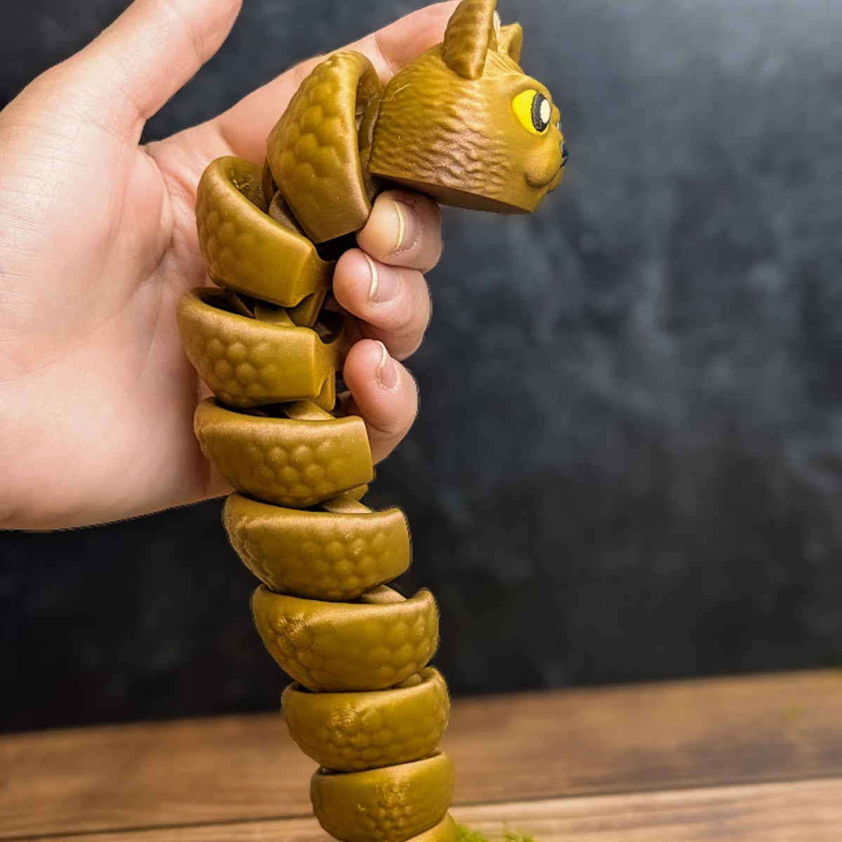 The Snat held upright in one hand, coiled downward like a spiral, showing off its poseable segments and textured body.