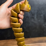 The Snat held upright in one hand, coiled downward like a spiral, showing off its poseable segments and textured body.