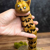 Vertical image of the Snat figurine stretched out while held in a hand, showcasing the full length of its flexible form and triangular tail.