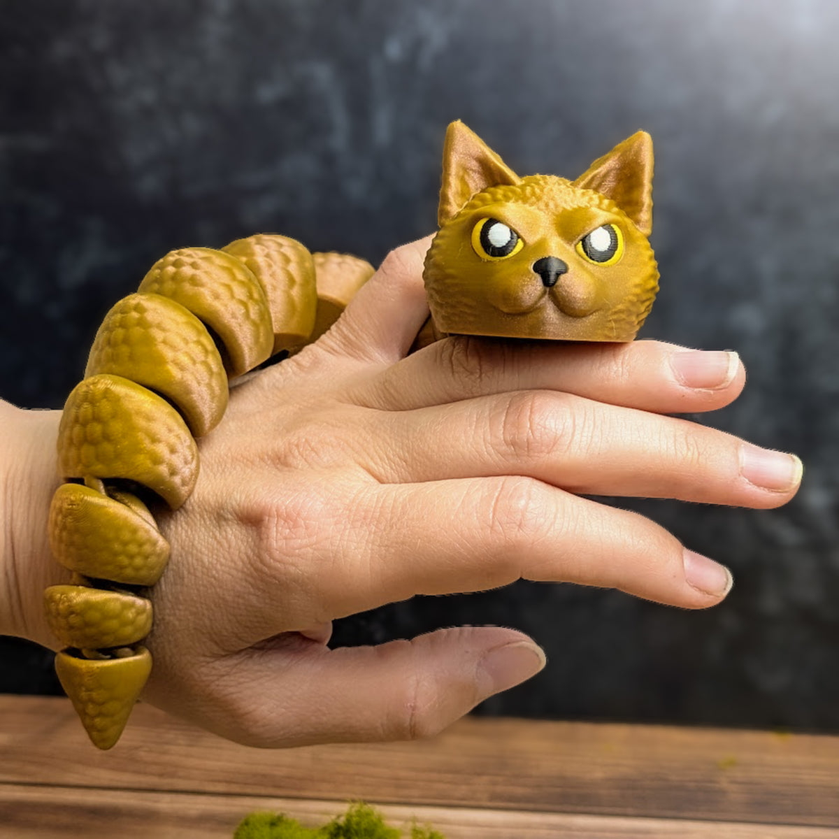 The articulated Snat figurine wrapped loosely around a hand, displaying its long flexible snake body and expressive feline head.
