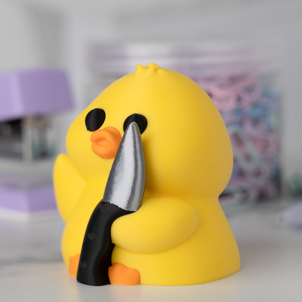 Yellow duck holding a knife with a blurred background