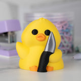 Front view of a yellow duck holding a knife with a blurred background