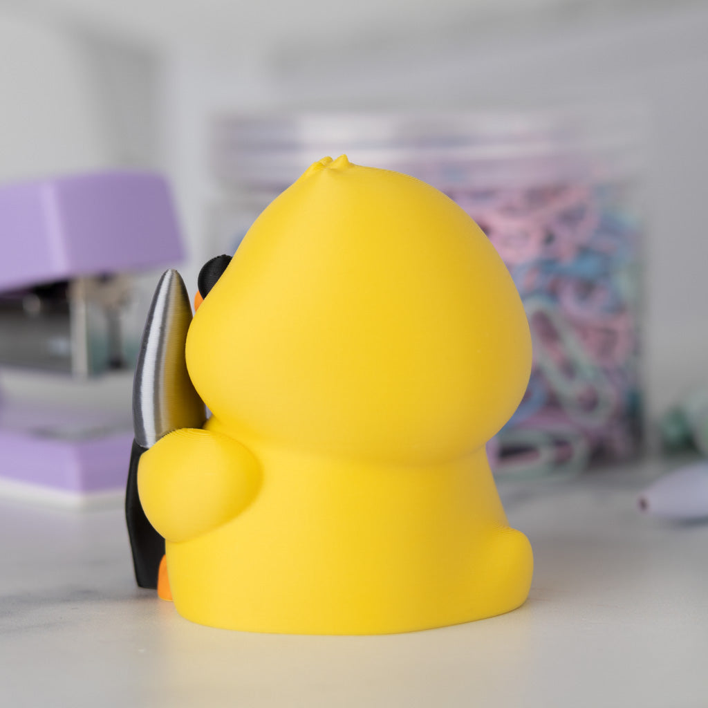 Side view of a yellow duck with a knife on a blurred background