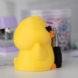 Side view of a yellow duck with a knife on a blurred background.