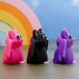 Side view of pink, black, and purple bat figurines lined up in a row