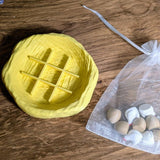 Yellow nest-shaped tic tac toe board beside a drawstring bag filled with chicken and egg pieces.