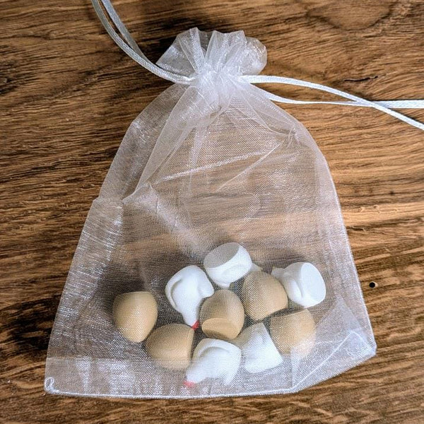 Transparent organza drawstring bag containing small chicken and egg pieces, resting on a rustic wooden table.