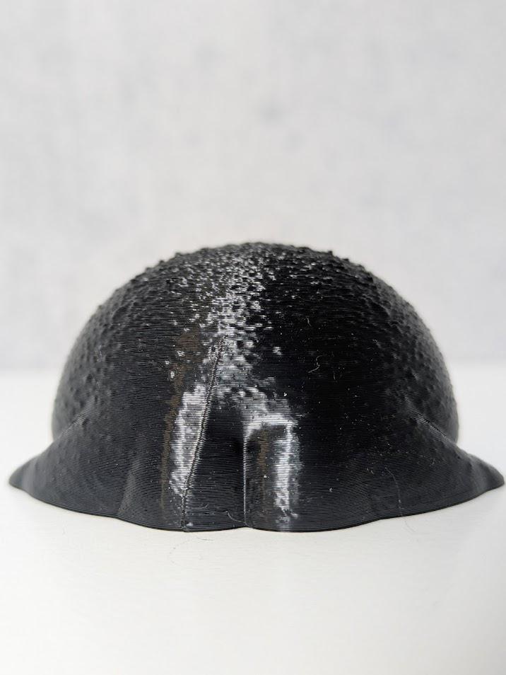 A tiny black rainfrog figurine viewed from behind, showcasing its unexpectedly well-defined frog butt.