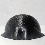 A tiny black rainfrog figurine viewed from behind, showcasing its unexpectedly well-defined frog butt.
