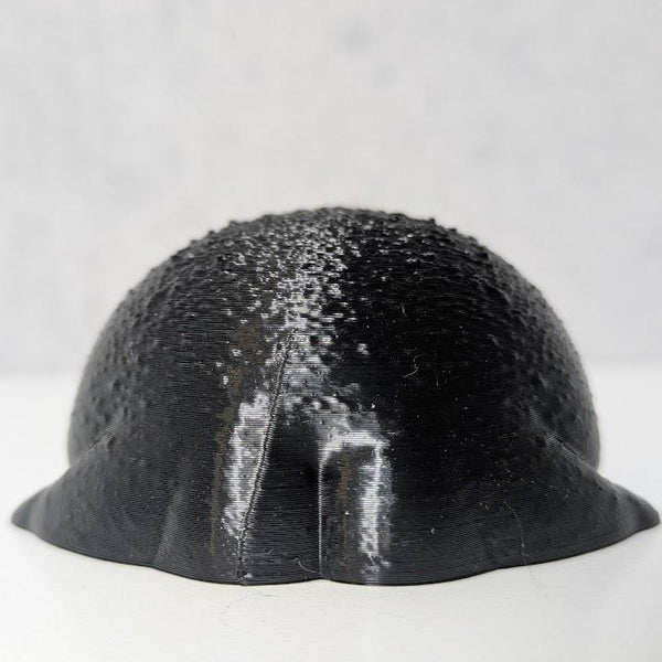 A tiny black rainfrog figurine viewed from behind, showcasing its unexpectedly well-defined frog butt.