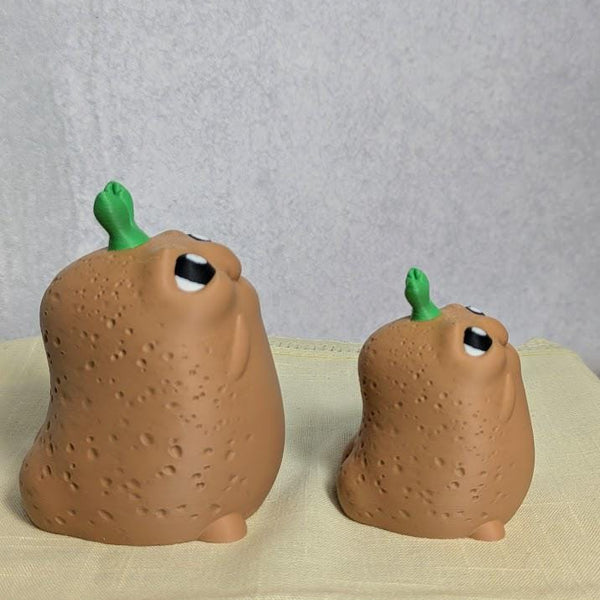 Side view of large and small Emotional Support Potatoes™, showing their sprouted tops and chunky shapes.