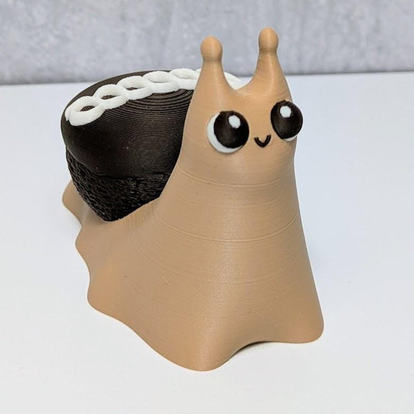 Cute dessert snail with a chocolate cupcake shell and white frosting swirl on its back, looking forward with big cartoon eyes.