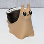 Cute dessert snail with a chocolate cupcake shell and white frosting swirl on its back, looking forward with big cartoon eyes.