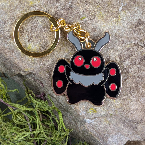 Cute Mothman keychain with red eyes placed on natural stone background