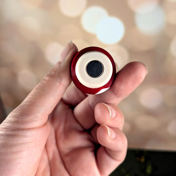 Underside of a red mushroom piece showing embedded magnet in the base for stability on the board.