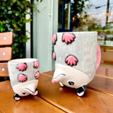 Two possum shaped coffee mugs sitting on a wooden surface, they are upside down. 
