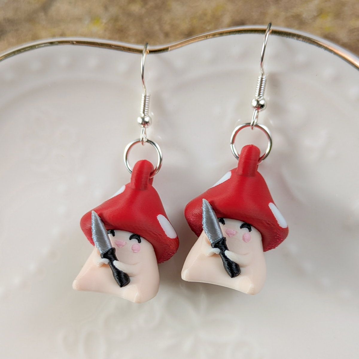 Close-up of Shroomshank mushroom earrings on white ceramic plate