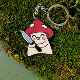 Keychain with mushroom character holding a knife on a green moss background
