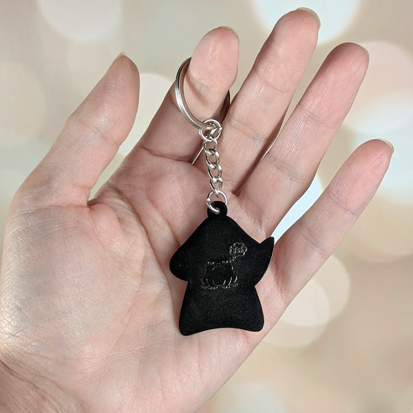 Back view of Shroomshank mushrom keychain in hand showing silver black metal and engraved frog