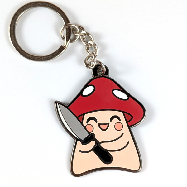 A cute enamel keychain featuring a mushroom holding a knife.